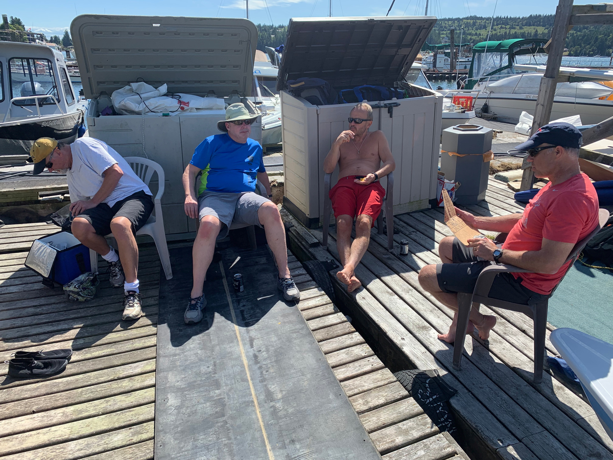 Thomas Andersson, Brian Lyseng and Grzegorz Krolikowski enjoy the shade and some cool drinks as Brian Fournier tabulates the scores from the 2019 Poise Cove Regatta.