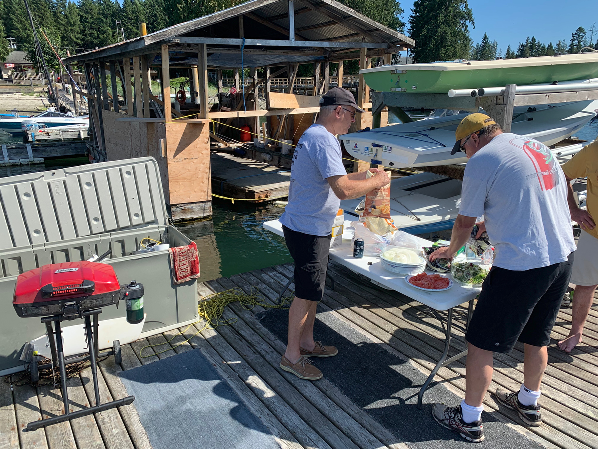 Dennis Olson opening up the chips and Thomas Anderson fixes the salad during the BBQ of the 2019 Poise Cove Regatta