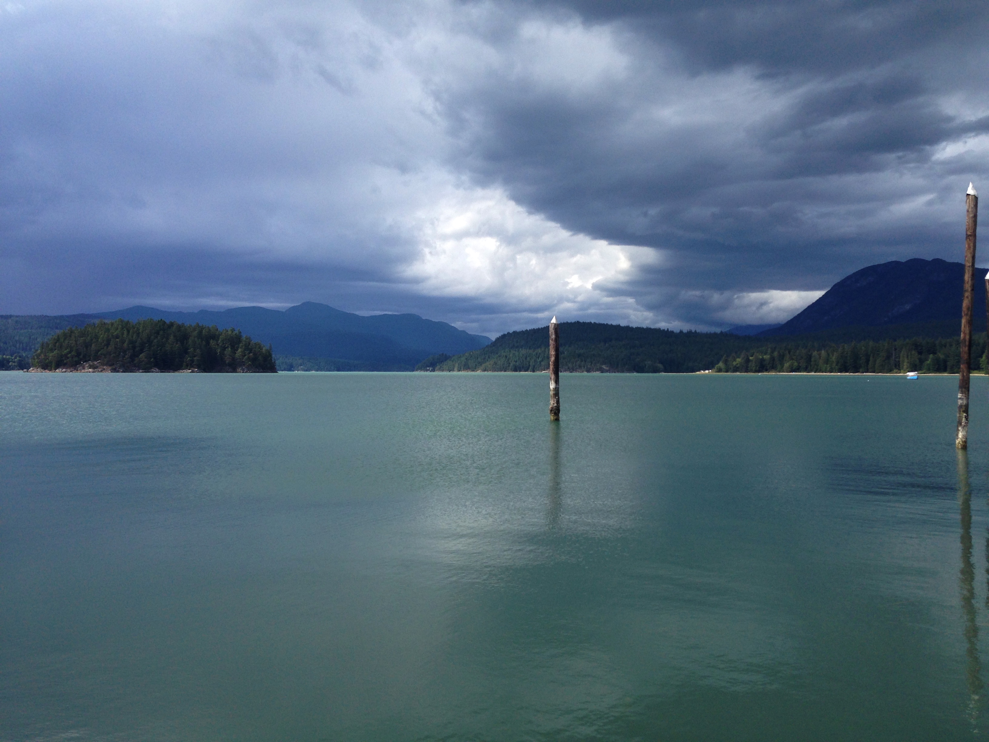 The green waters of the Sechelt Inlet due to an micro-algae bloom called cocclithophorids with a rain storm on the horizon.